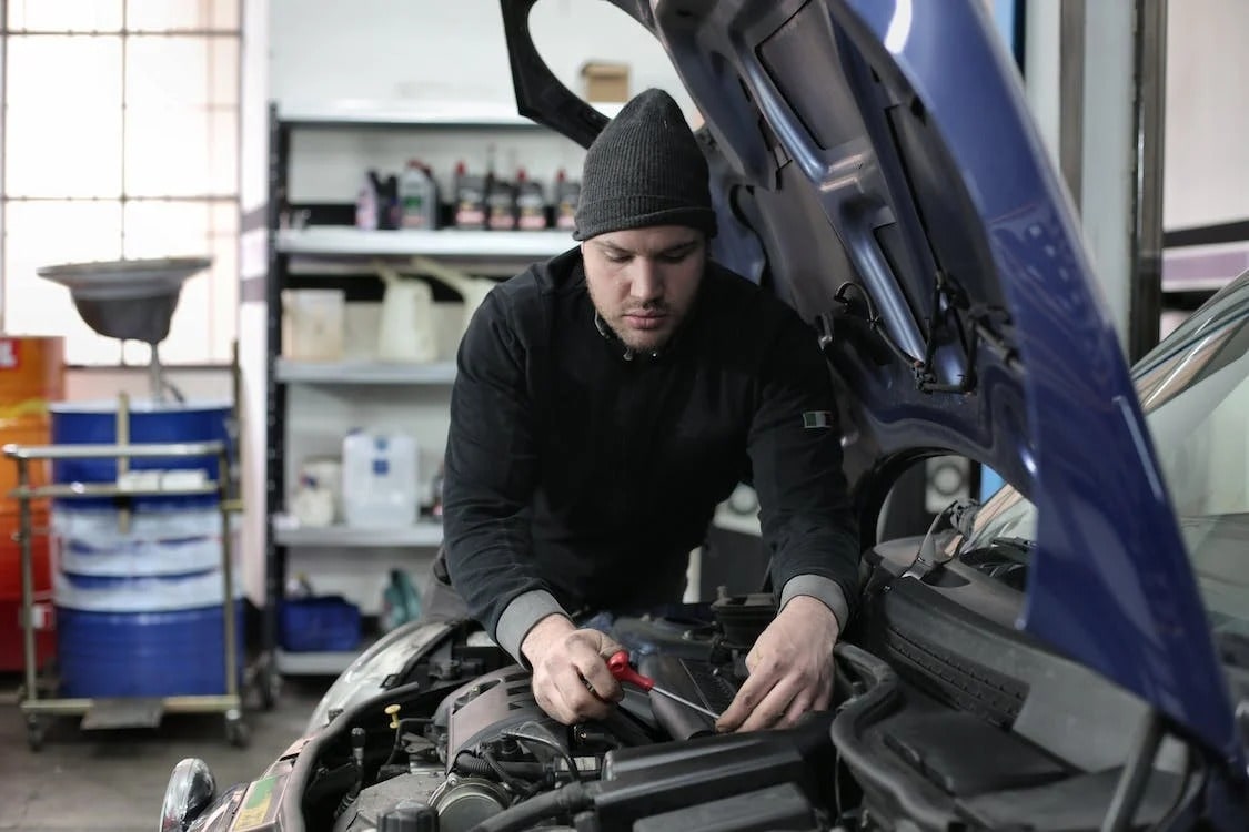 A mechanic under the hood of a blue car