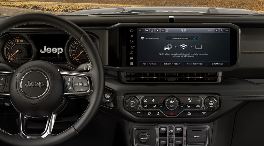 Interior dashboard look at a 2026 Jeep Wrangler interior in Summit showing the wide landscape format Uconnect touchscreen