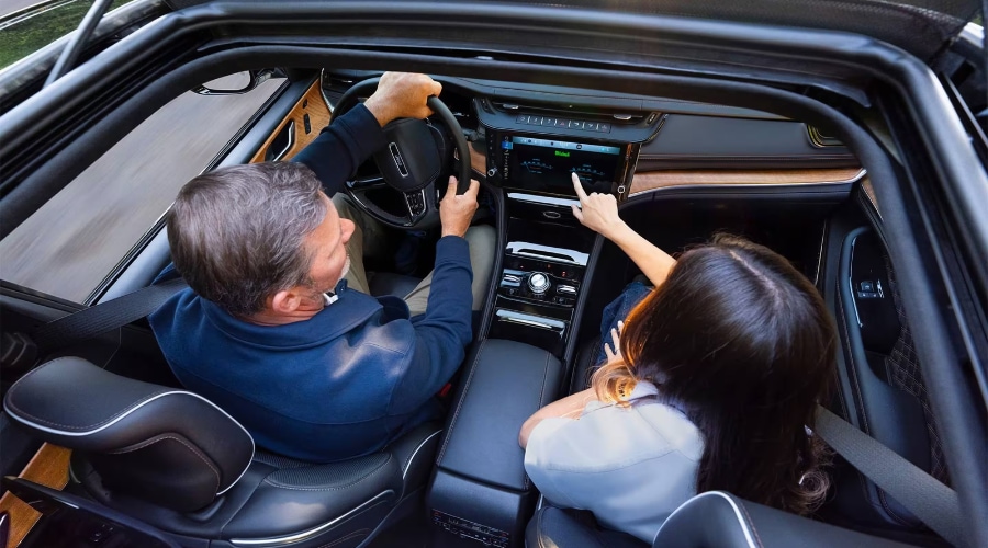 Overhead view of the 2027 Jeep Grand Cherokee cockpit featuring a front passenger using the Uconnect 5 touchscreen display with McIntosh audio, available at Salerno Duane Chrysler Jeep Dodge Ram in New Jersey.