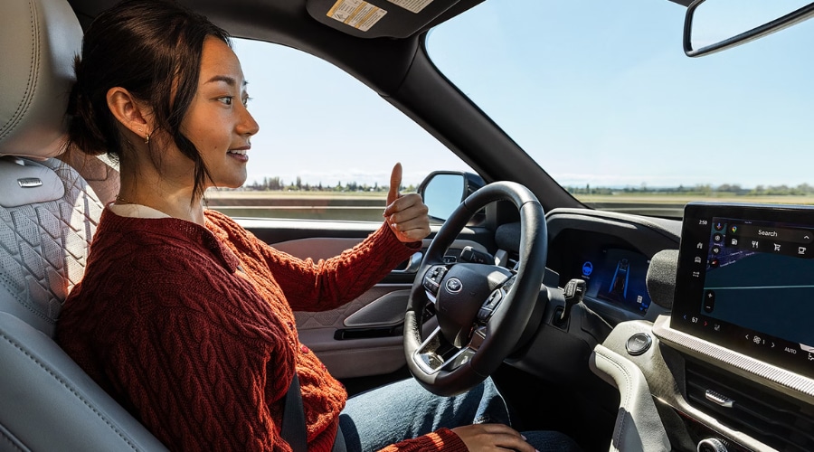 Driver giving a thumbs-up inside a 2026 Ford Explorer Platinum using Ford BlueCruise hands-free highway driving support, displaying native Google Maps navigation on the 13.2-inch central touchscreen during a daily commute along I-78 in Summit, NJ.