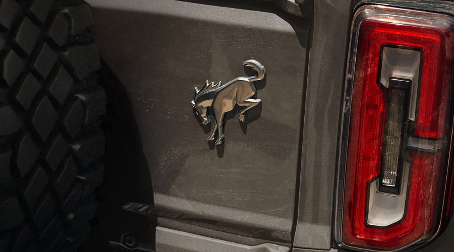 Close-up of the iconic chrome bucking horse emblem and rear LED taillight on a 2026 Ford Bronco tailgate, available at Salerno Duane Ford near Summit, NJ.