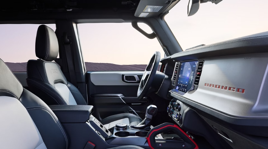 Front cabin view of the 2026 Ford Bronco interior featuring two-tone leather seats, 12-inch SYNC 4 touchscreen, and branded dashboard badge for daily commutes in Summit, NJ.