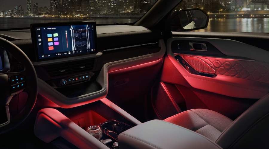 Interior cabin view of the 2027 Ford Explorer showcasing red customizable LED ambient lighting along the dashboard, footwells, and quilted door trim, with the 13.2-inch touchscreen displaying ambient light controls at Salerno Duane Ford near Summit, NJ.