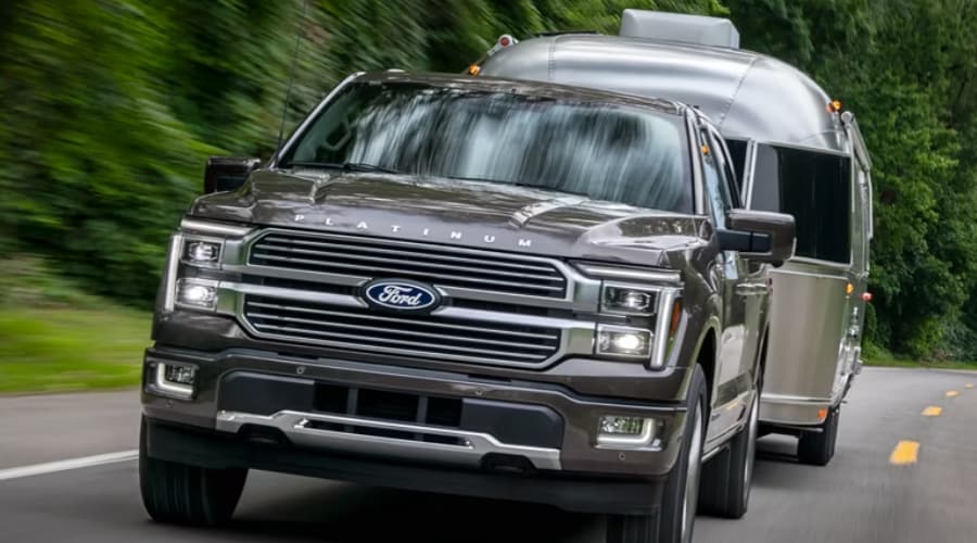 A 2026 Ford F-150 cruising on a local highway while hauling a travel trailer, showcasing real-world towing stability for Union County weekend getaways