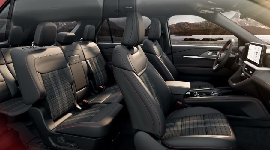 A side-profile cutaway view of the 2026 Ford Explorer interior, showcasing the spacious three-row seating configuration with premium black upholstery, sporty red contrast stitching, and generous rear legroom.