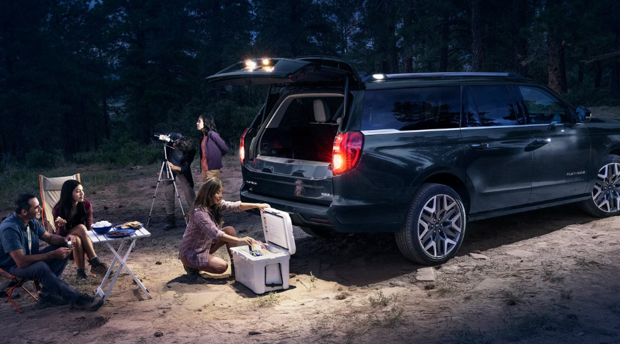 Family camping at night using the Power Ford Split Gate tailgate lighting and bench seating on a 2027 Ford Expedition MAX Platinum at Salerno Duane Ford near Paramus, NJ.