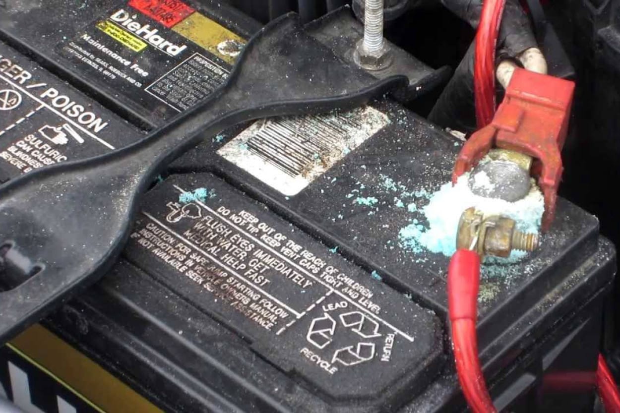 Close up of a car battery with visible corrosion on the terminals.