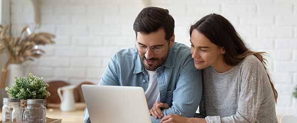 Two people sitting at a table looking at a laptop