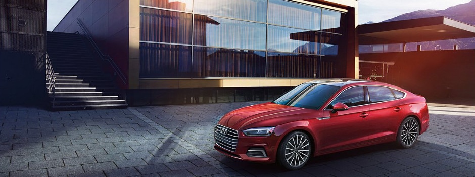 A red Audi A5 Sportback parked outside a house.