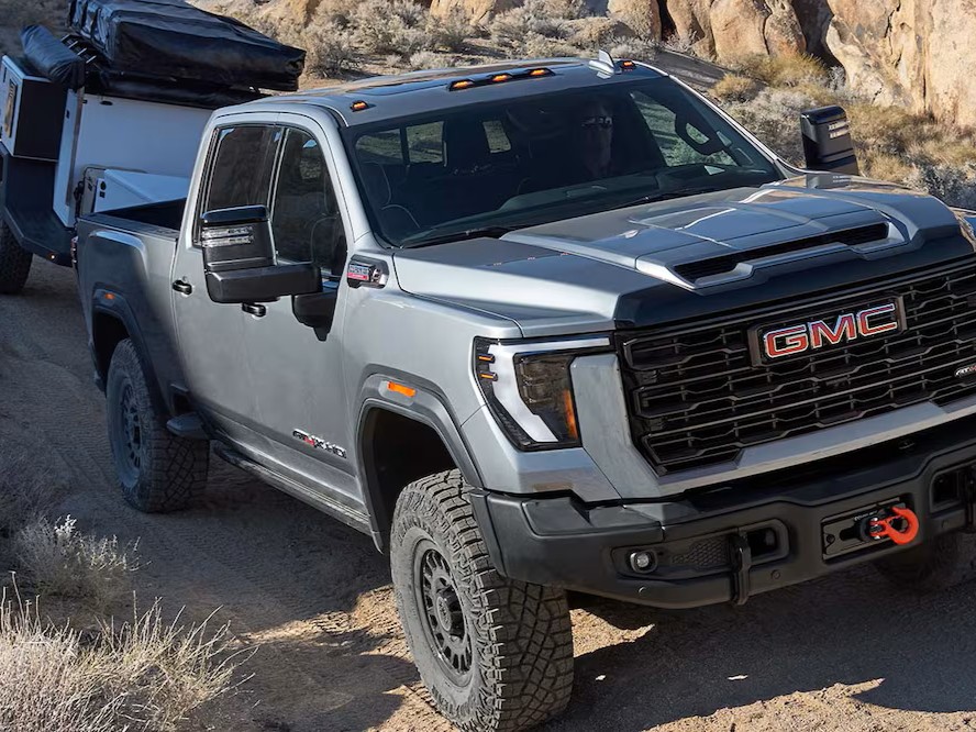 The 2026 GMC Sierra HD AT4X AEV Heavy Duty Off-Road Truck Hauling a Trailer Through a Dirt Road