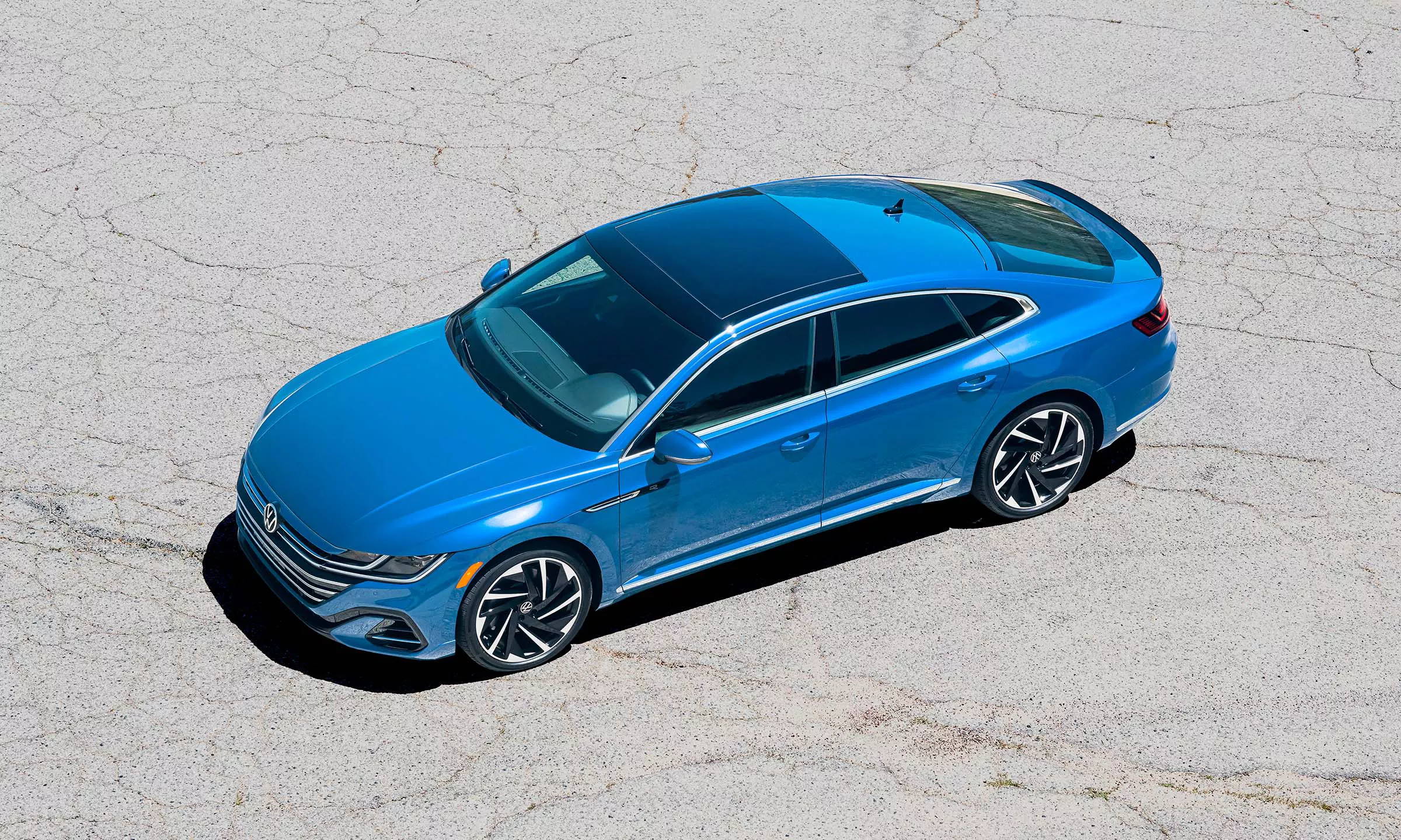 A birds-eye view of a n Arteon shown in Kingfisher Blue Metallic parked on a pale gray concrete road.