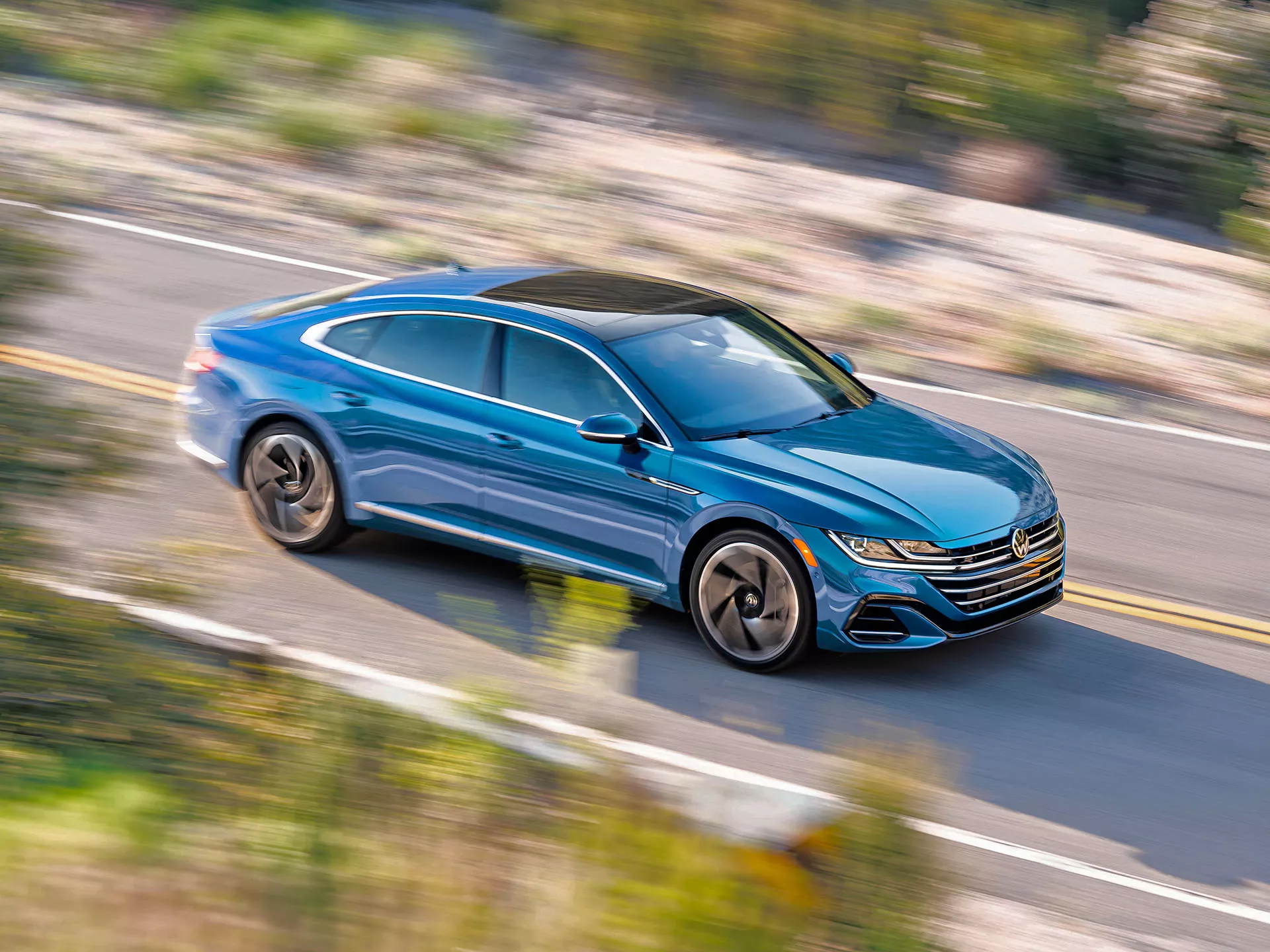 A quickly accelerating Atreon shown in Kingfisher Blue Metallic blurs the shoulder and roadside vegetation around it.