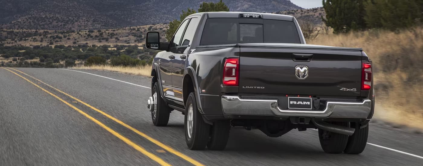 Grey 2024 Ram 3500 Limited driving down a road.