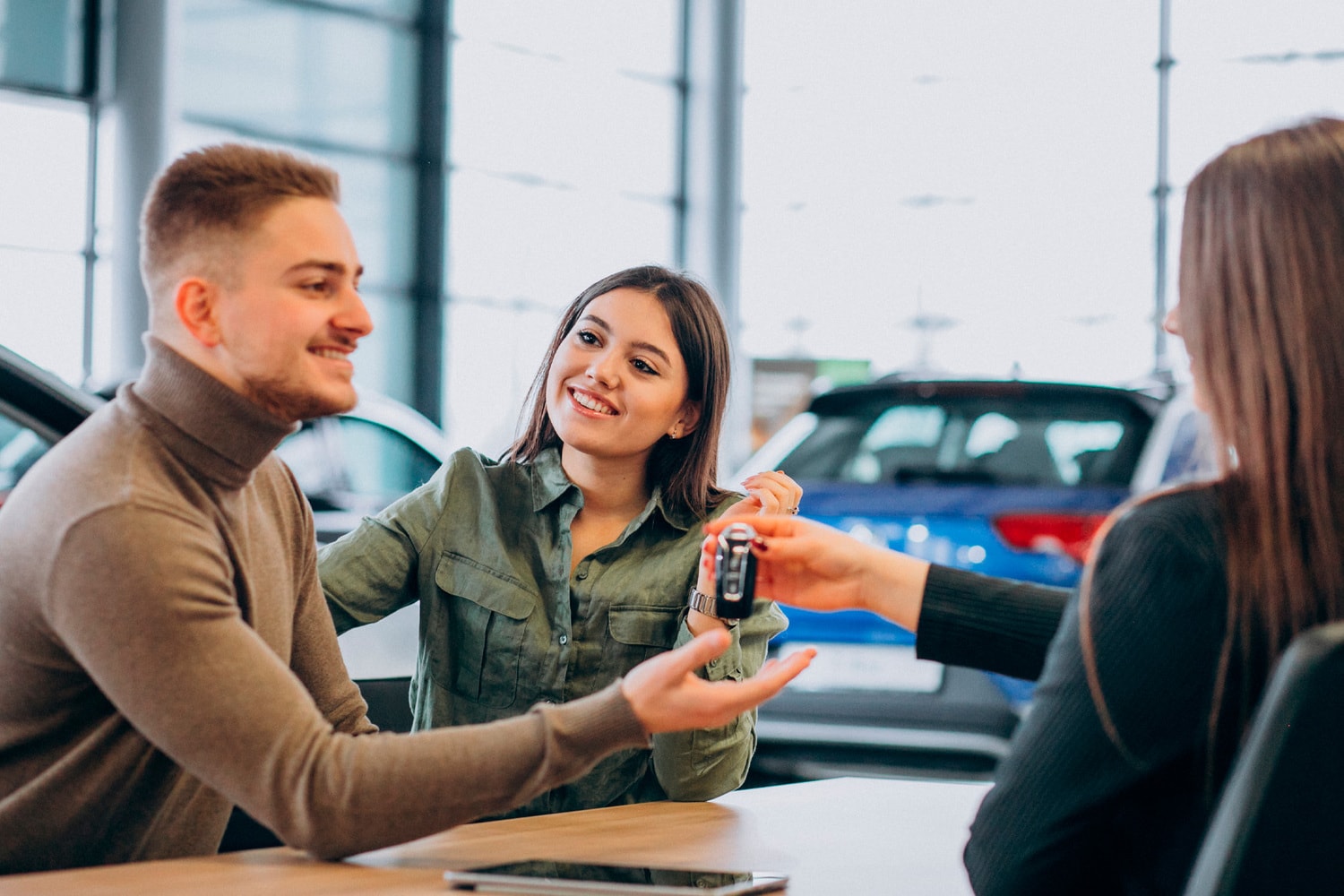 Couple receiving keys for new hybrid car after discussing financing