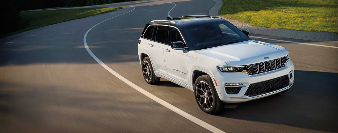 White 2025 Jeep Cherokee driving up a hill