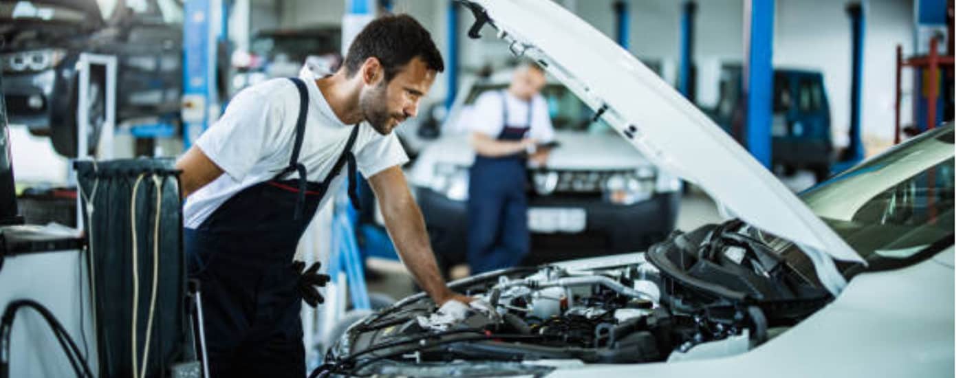 A mechnic looking under the hood of a car looking for the problem