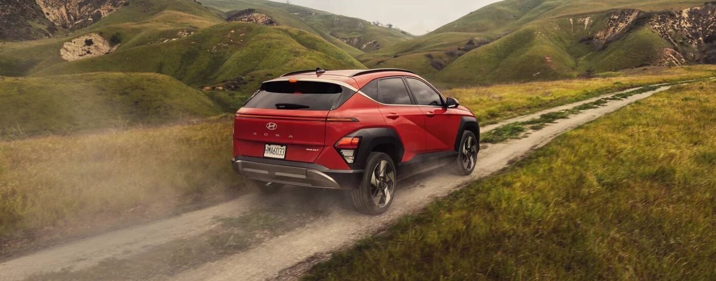 Red 2024 Hyundai Kona driving along a dusty trail