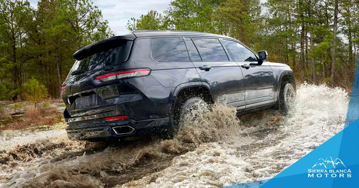 Black 2024 Jeep Grand Cherokee 4xe Driving Through Water in a Pine Tree Forest | Sierra Blanca Motors