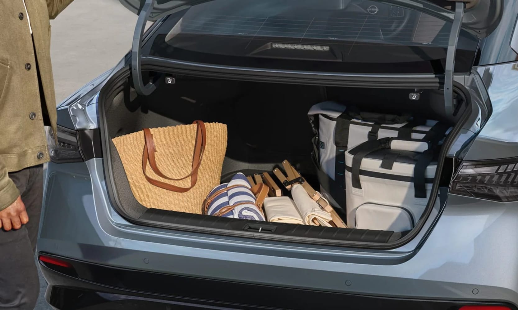 Exterior image of a person loading a 2027 Nissan Sentra SR's trunk with personal belongings