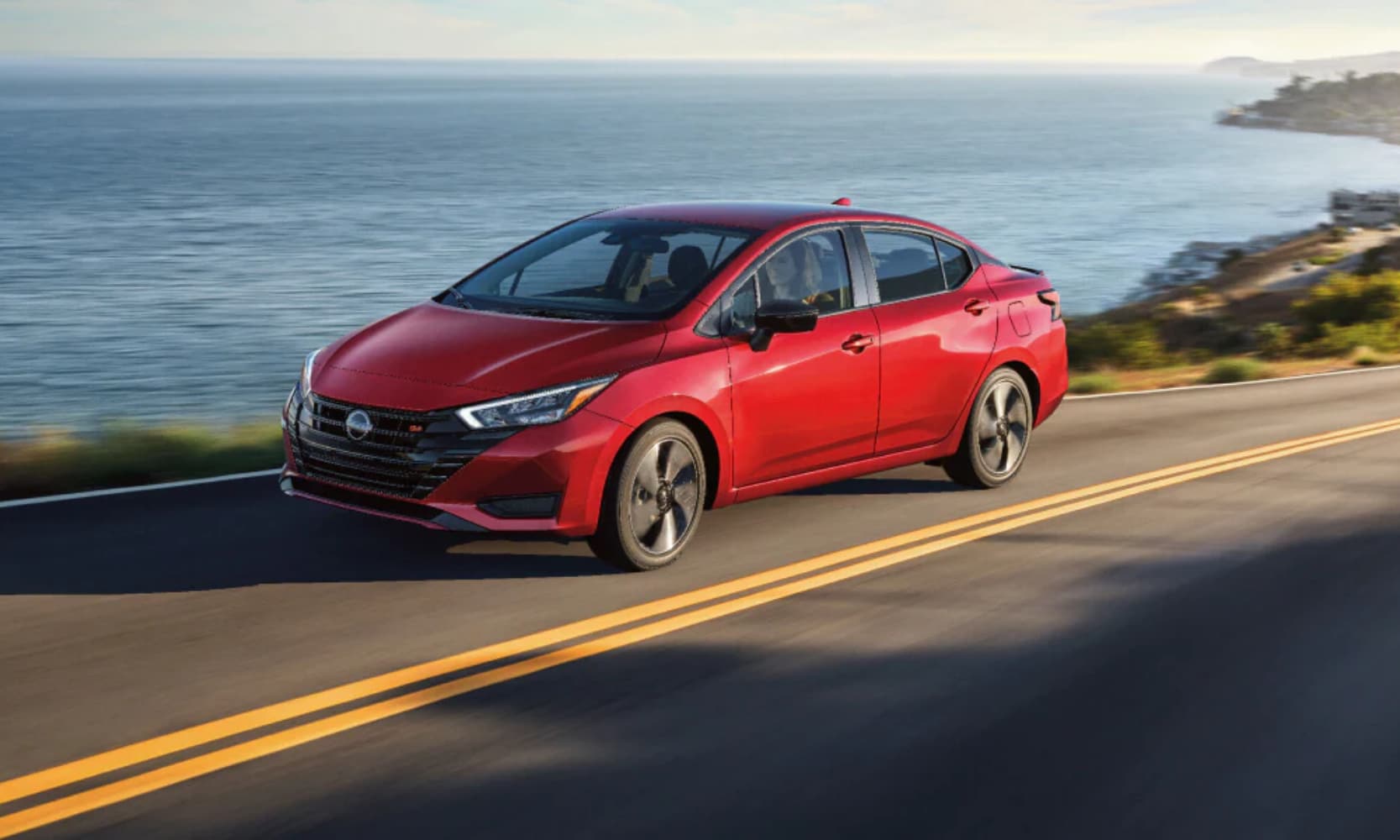 Exterior front angle image of a 2025 Nissan Versa SR driving down a coastal freeway