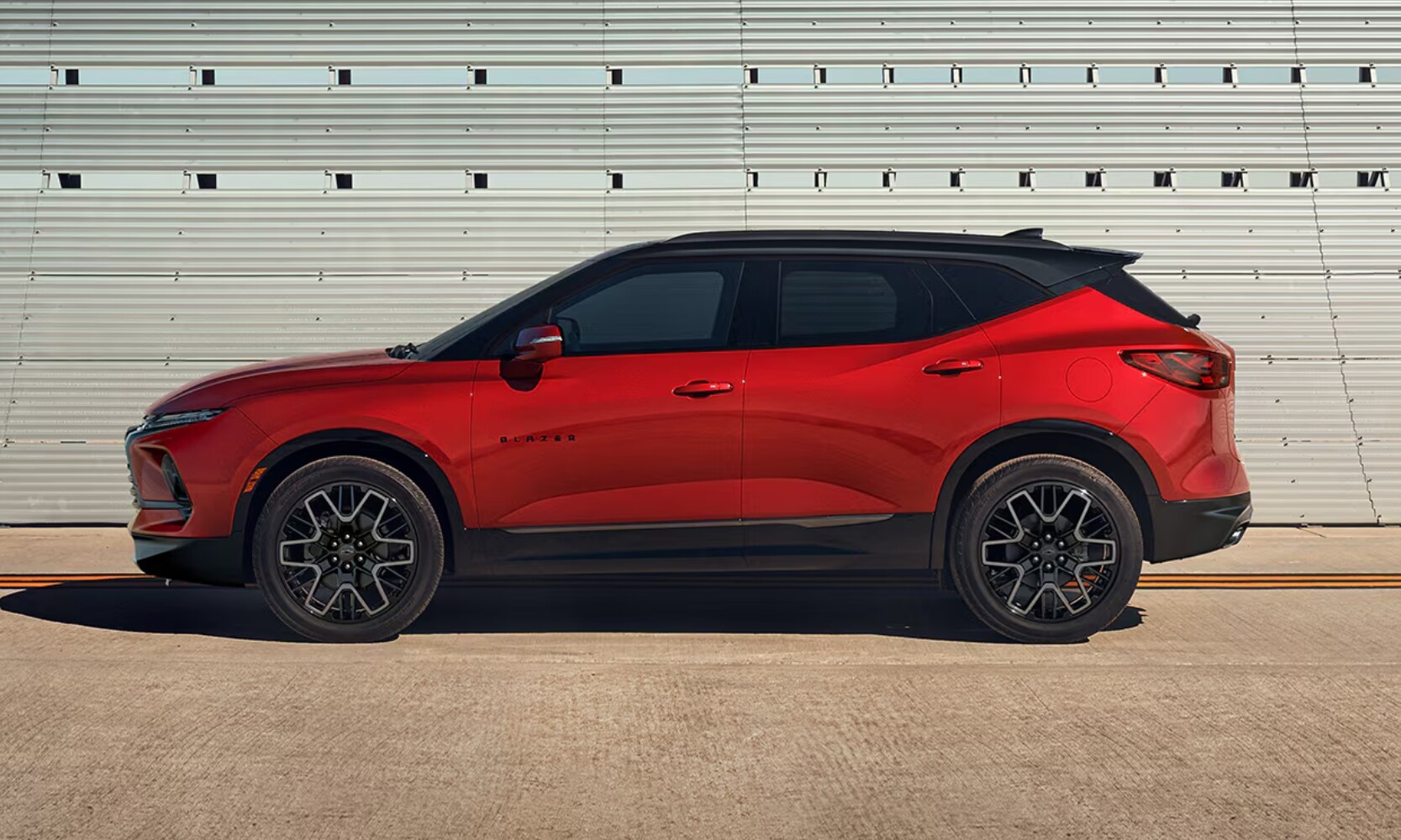 Exterior side profile image of a red 2024 Chevy Blazer parked on a road during the day