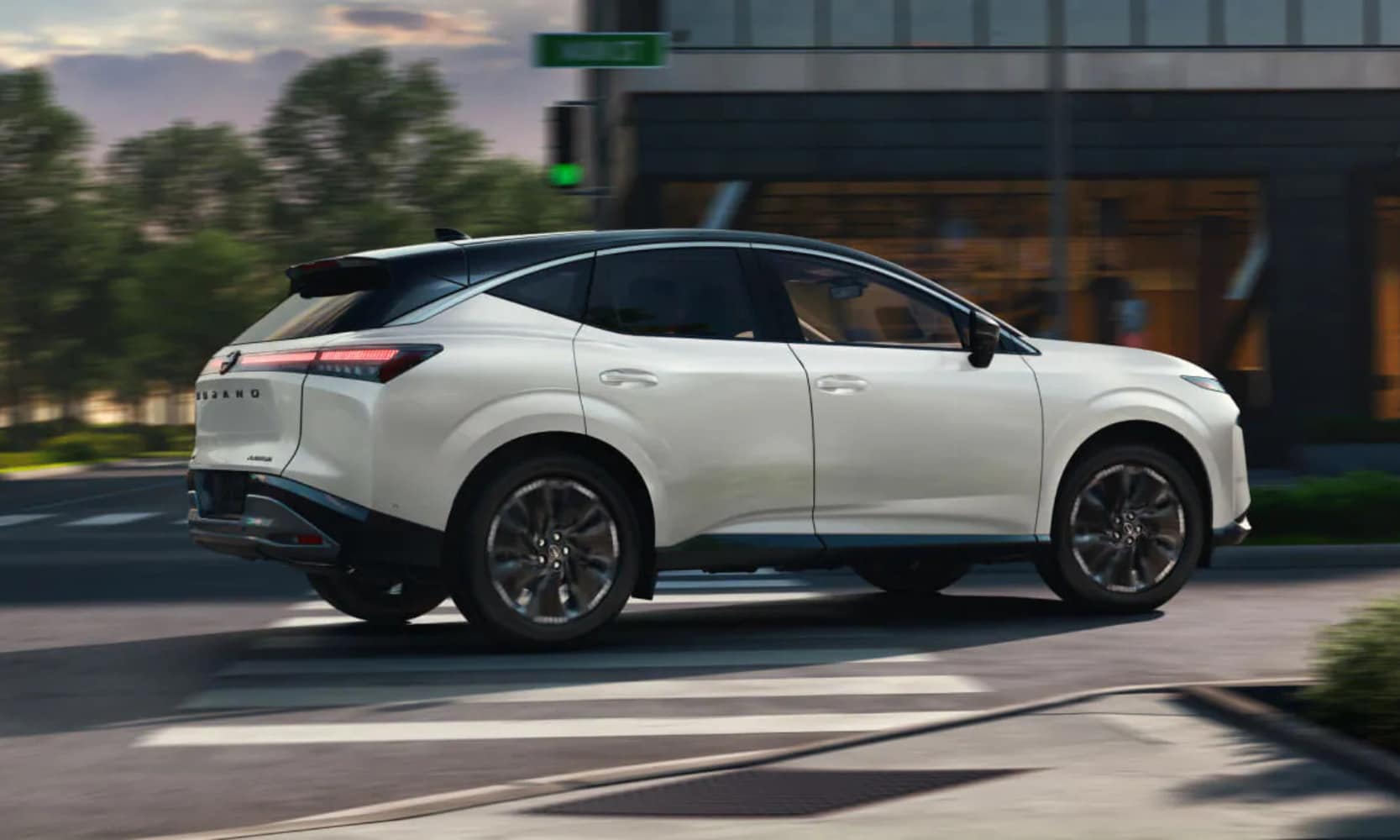 Exterior side image of a white 2025 Nissan Murano Platinum driving down a city street during the day