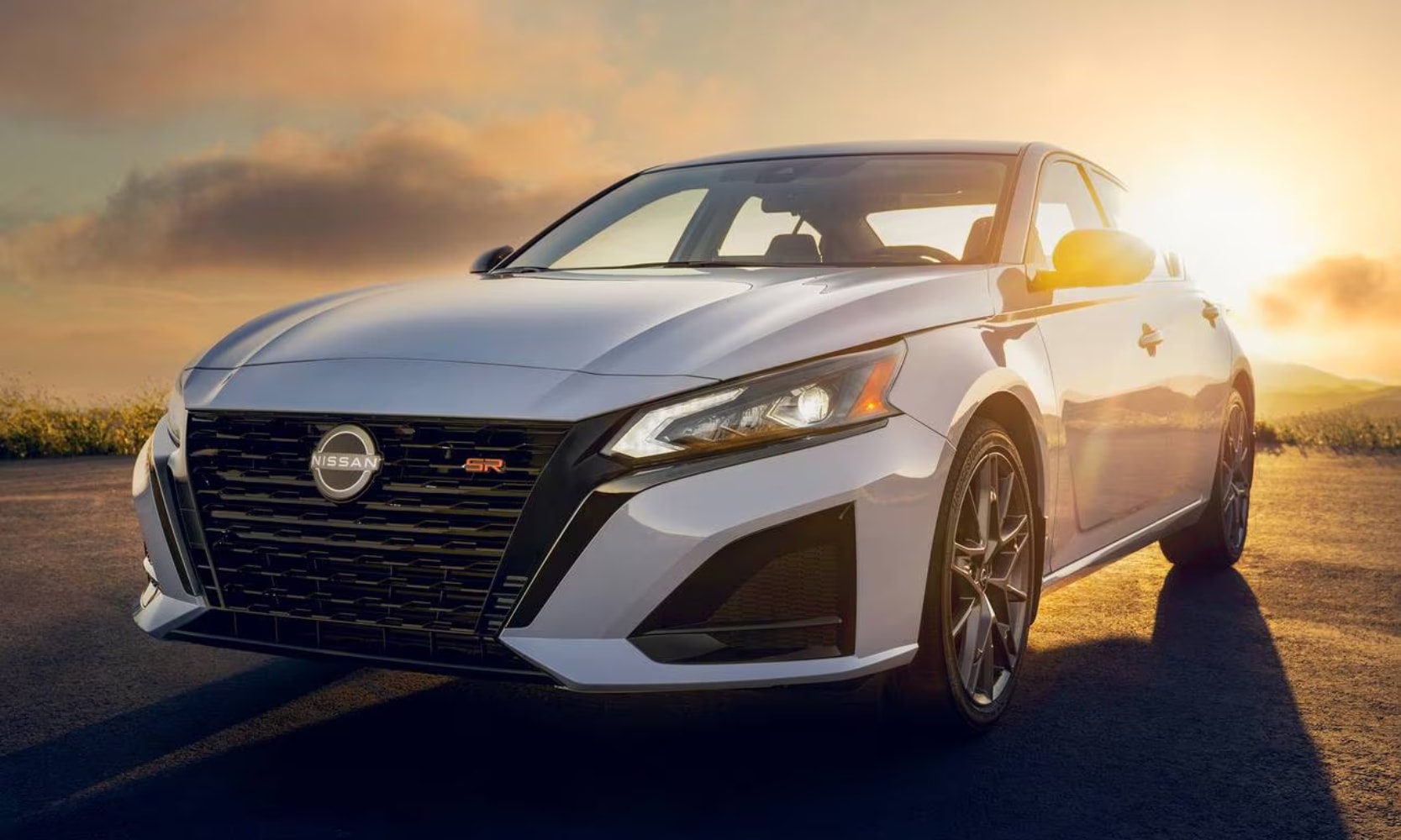 Closeup exterior image of a white 2023 Nissan Altima parked on a road during sunset