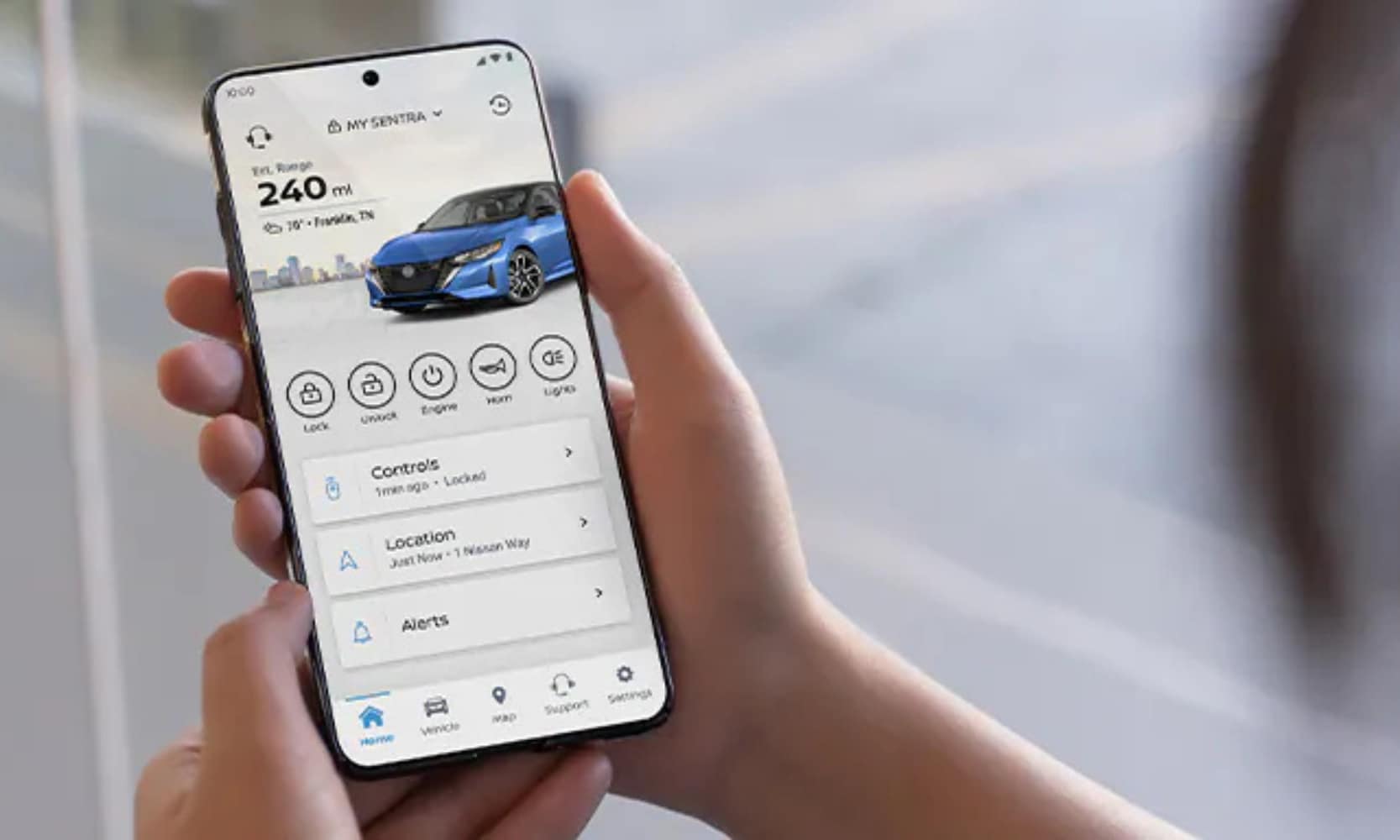 Closeup image of a person holding a smartphone with the MyNissan app showing their 2025 Nissan Sentra management dashboard
