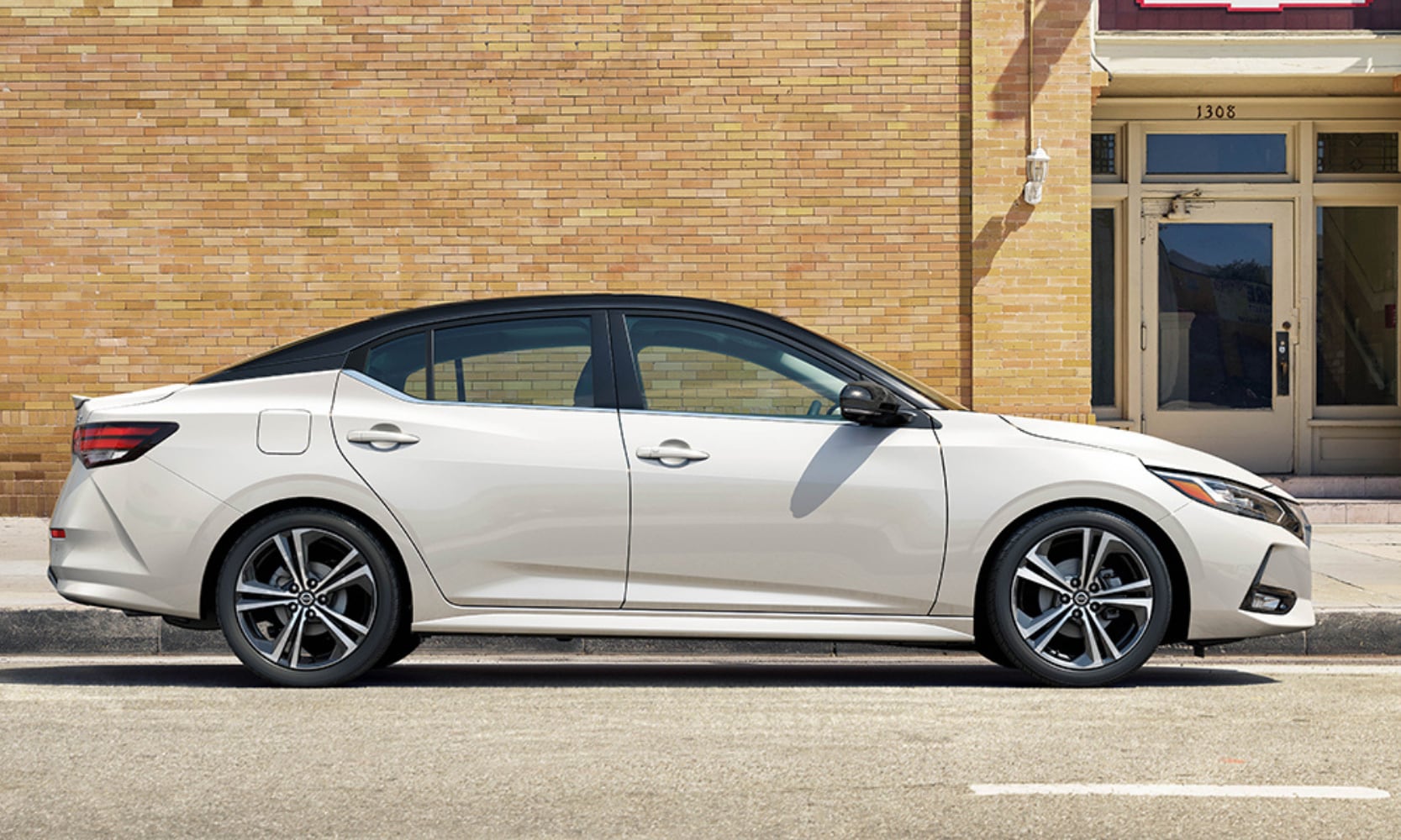 Side exterior image of a white 2023 Nissan Sentra parked outside a building on the street