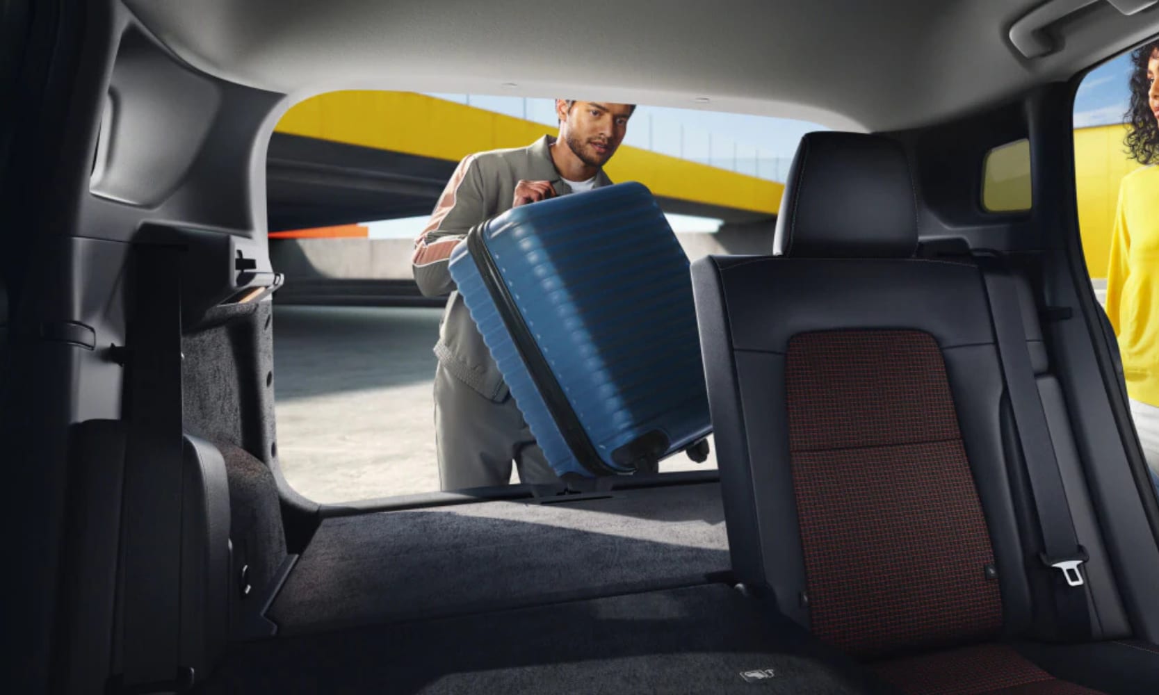 Interior image of the 2026 Nissan Kicks cargo area with the rear seats folded and a person loading a suitcase