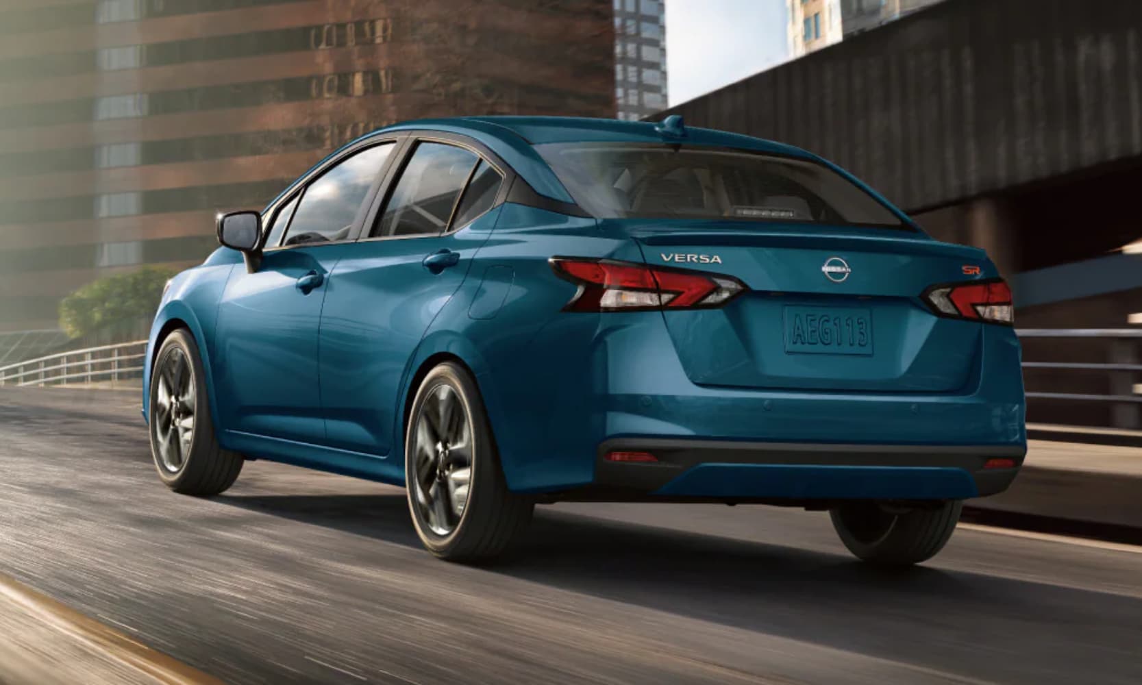 Exterior rear-view image of a teal 2025 Nissan Versa driving on a city open freeway