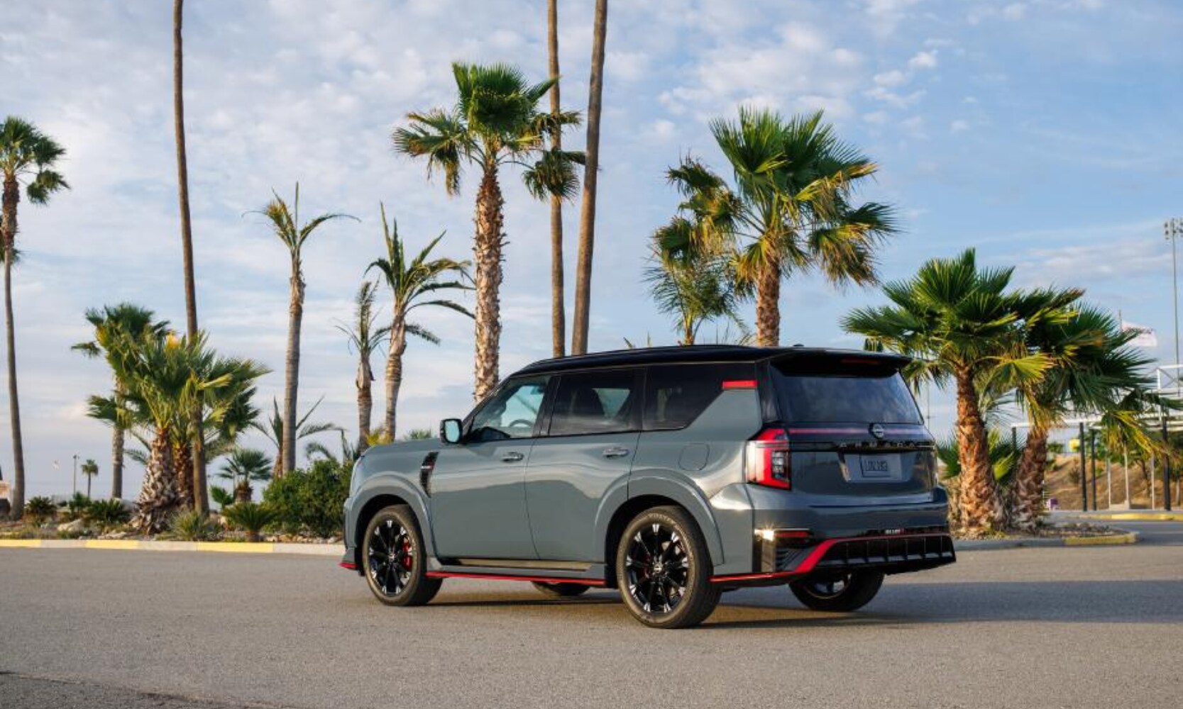 Rear side exterior image of the 2026 Nissan Armada NISMO parked on a street with surrounding palm trees