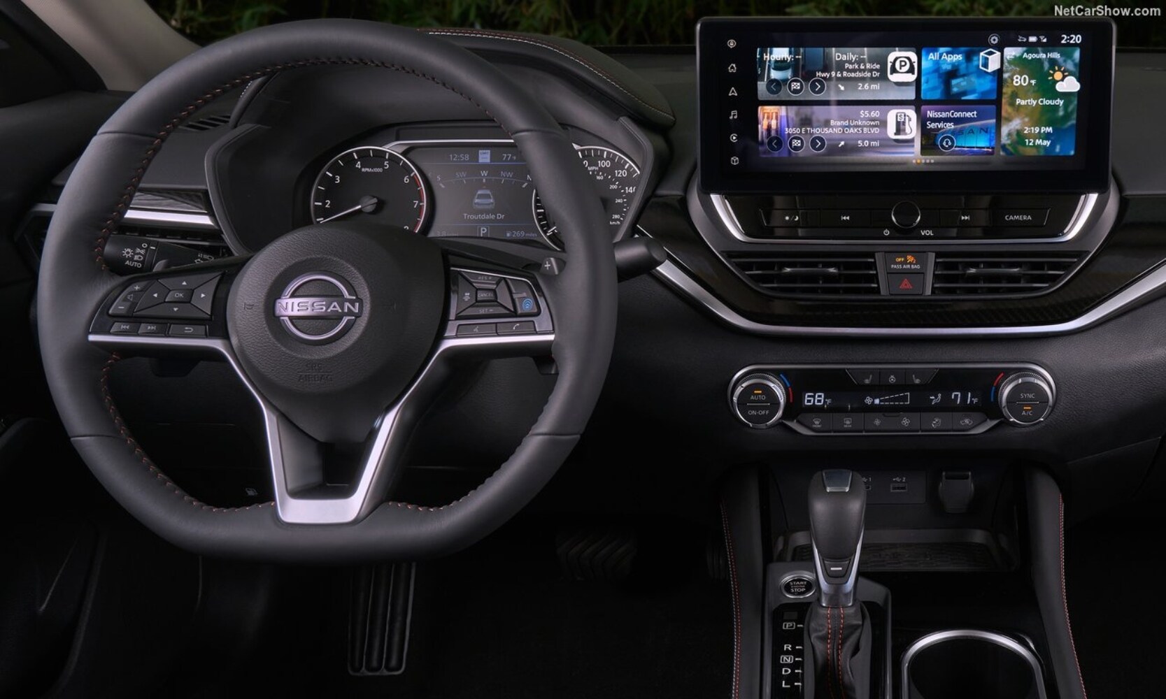 Closeup interior image of a 2023 Nissan Altima driver's seat area, steering wheel, and infotainment system in black colors