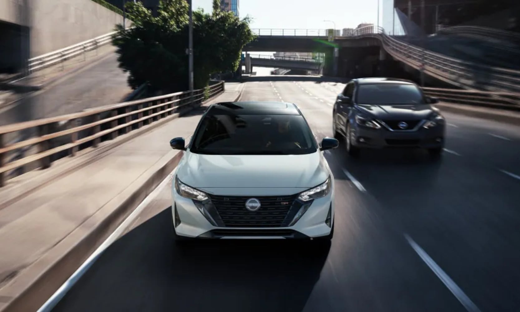 Front view image of a white and black 2025 Nissan Sentra driving down a freeway