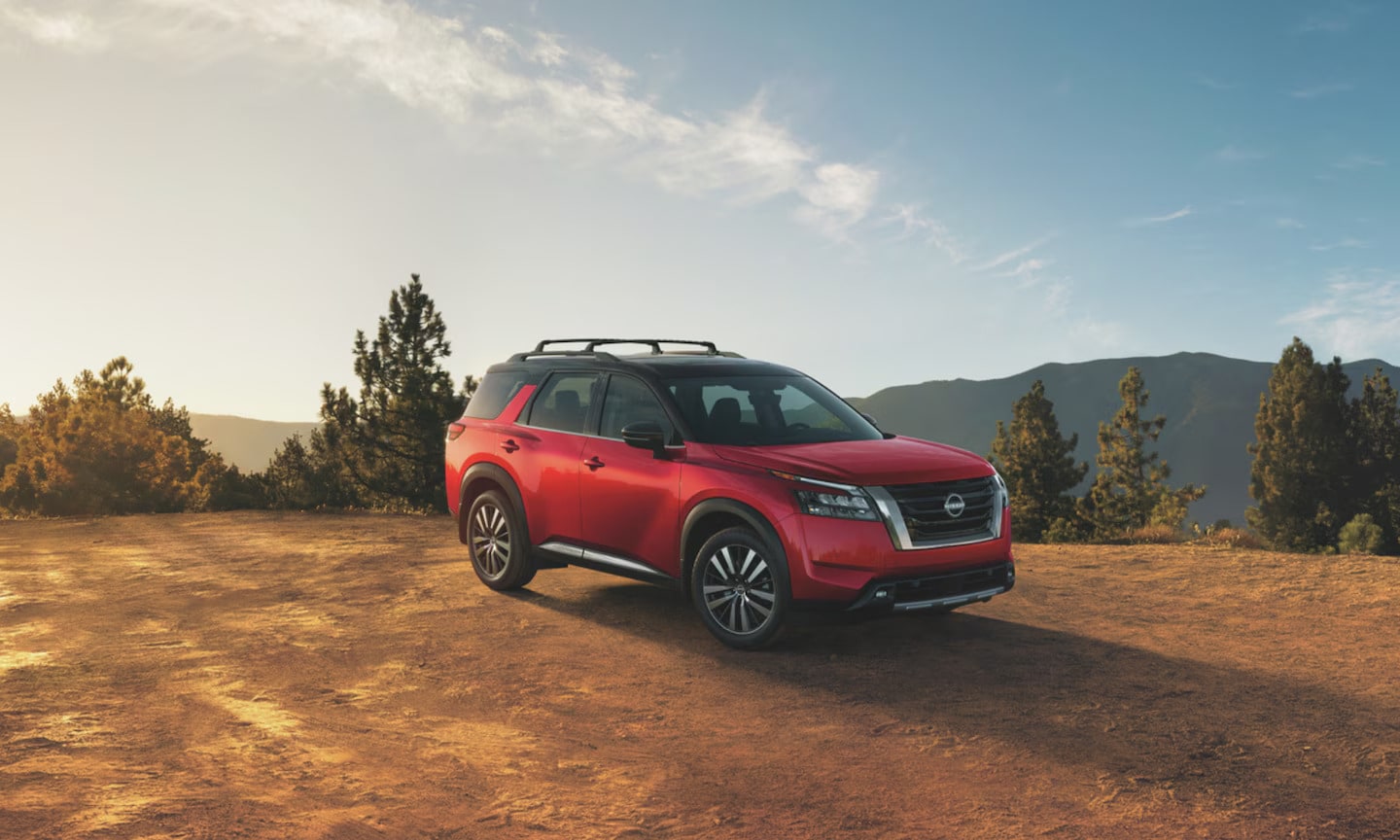 Exterior image of a red 2025 Nissan Pathfinder Platinum parked on top of a mountain