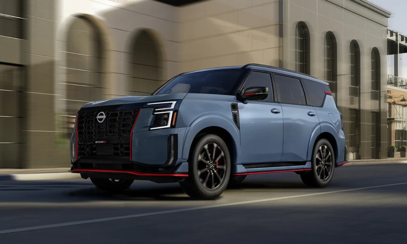 Exterior image of a blue and red trim 2027 Nissan Armada NISMO driving on a city street