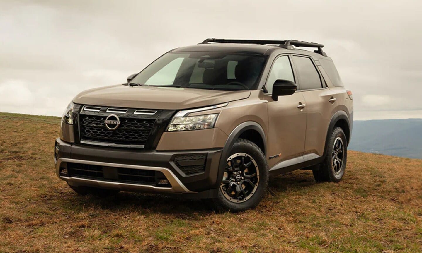 Exterior front image of a tan 2025 Nissan Pathfinder Rock Creek parked on top of a mountain