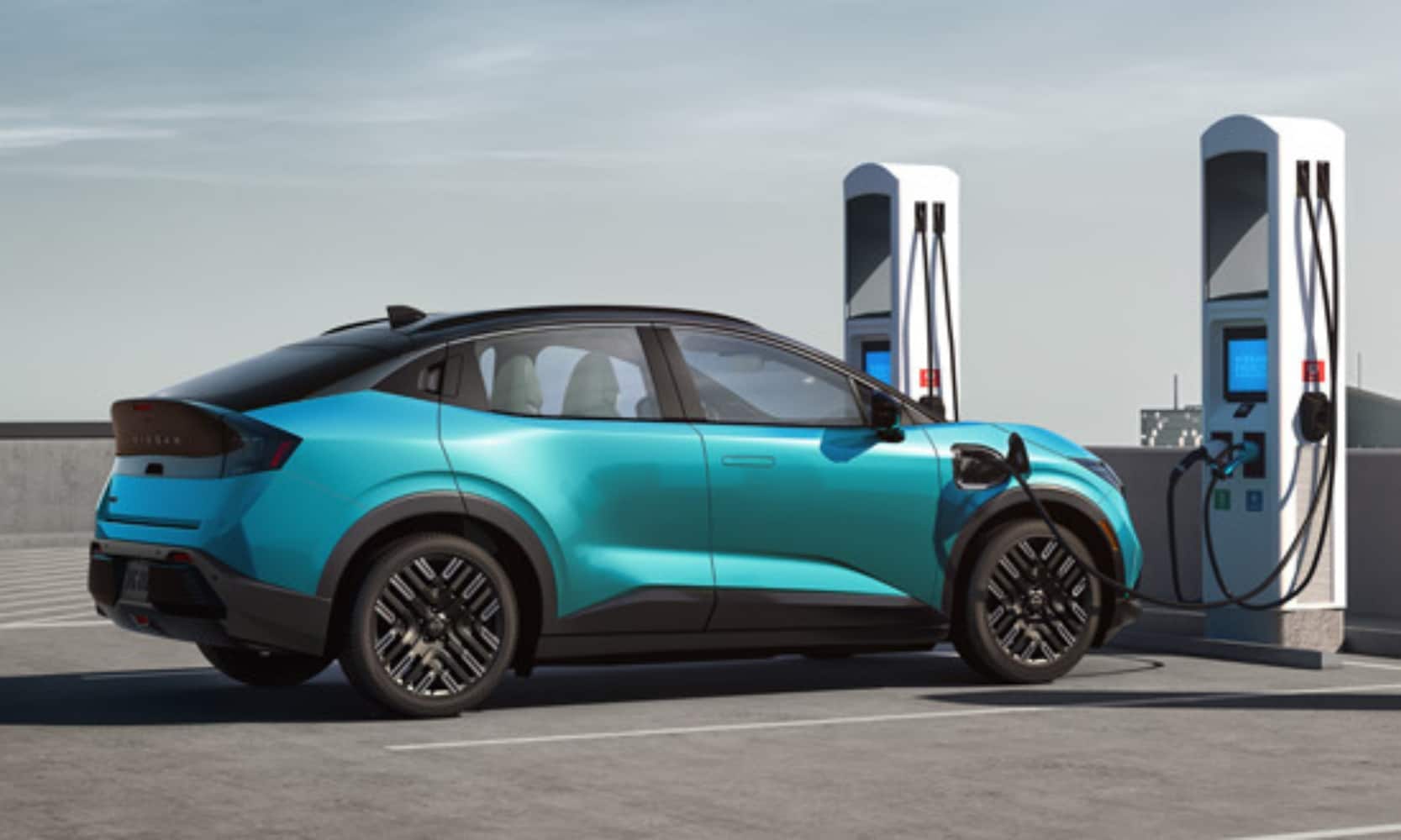 Exterior side image of an aqua blue 2026 Nissan LEAF Platinum+ charging on a rooftop parking garage