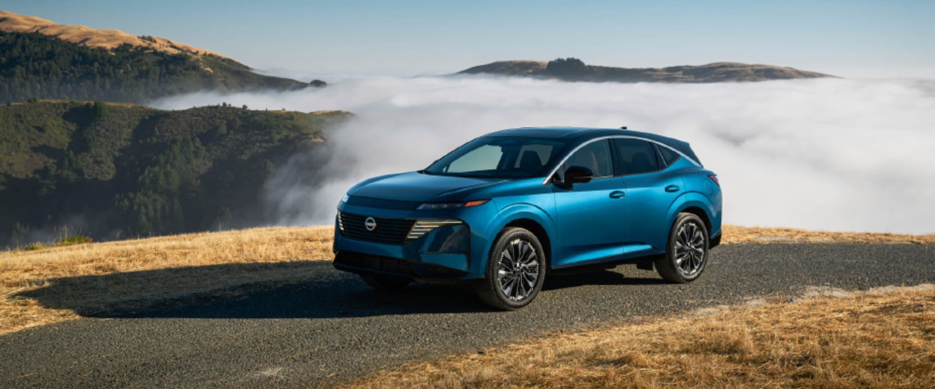 Exterior image of a blue 2025 Nissan Murano Platinum parked on top of a mountain