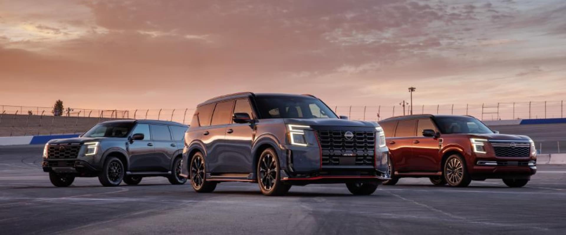 Exterior hero image of three 2026 Nissan Armada NISMO models parked in a raceway track during sunset