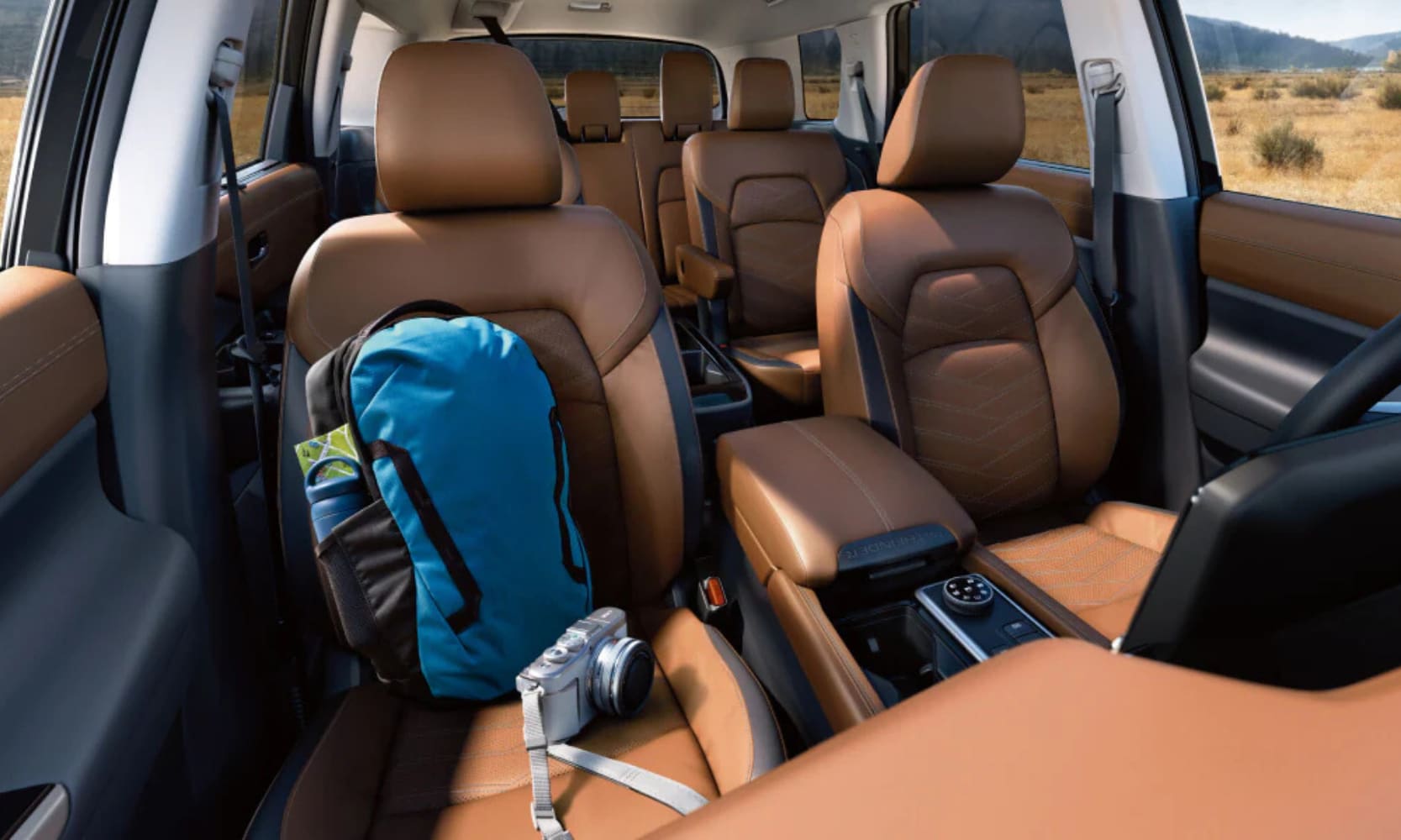 Interior image of the 2025 Nissan Pathfinder tan leather three-row seats with mountain field window views