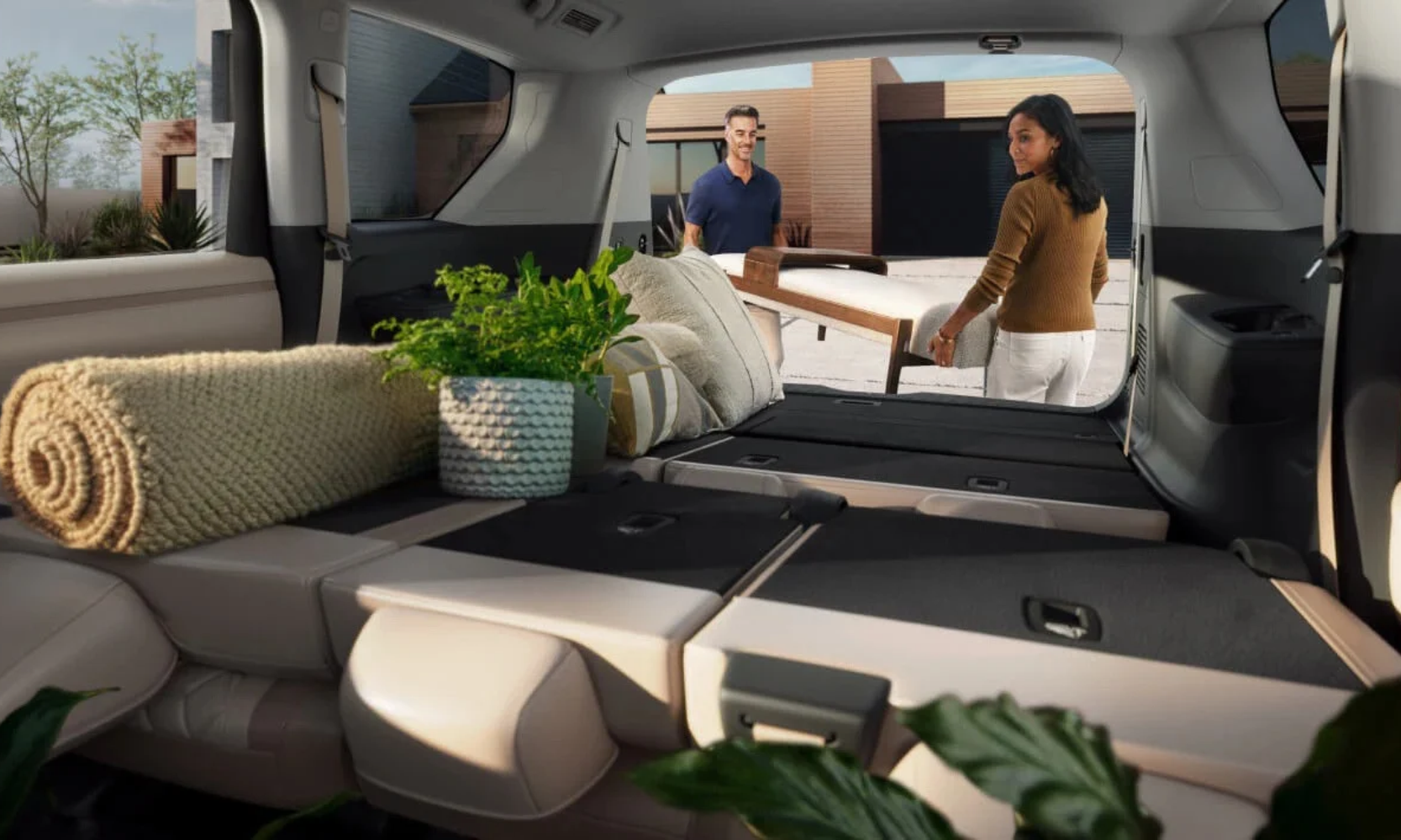 Image of two people loading furniture in a 2027 Nissan Armada trunk with the second and third row folded flat