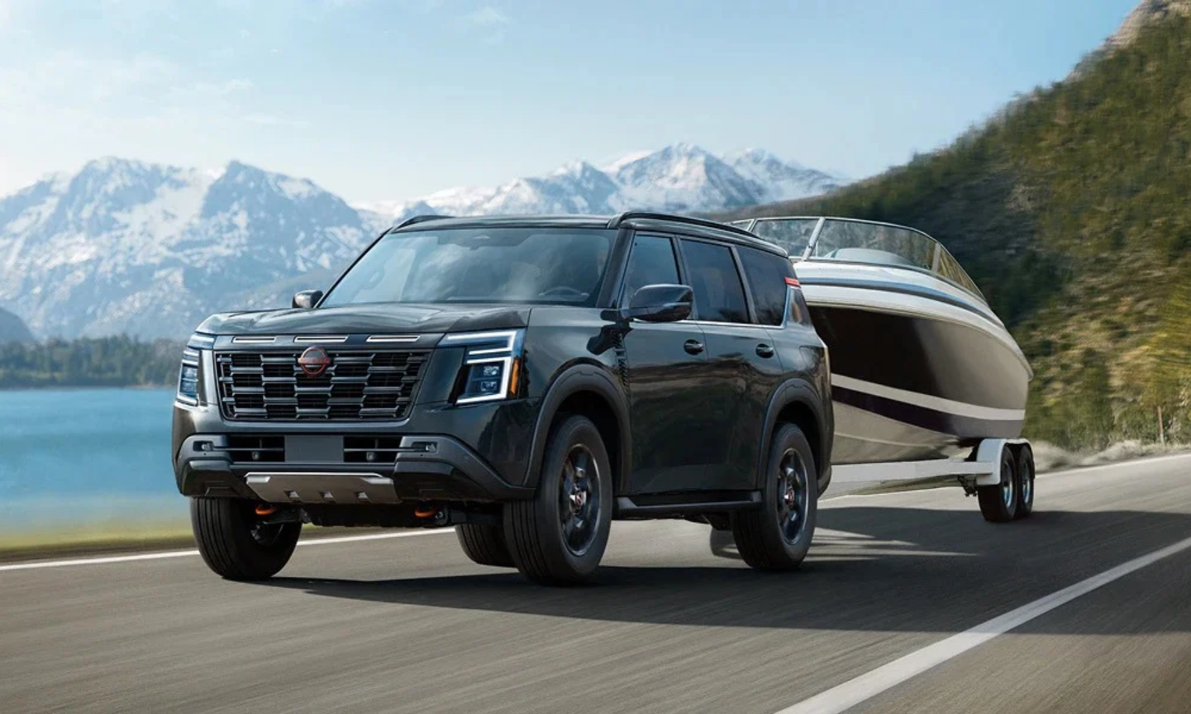 Exterior image of a black 2027 Nissan Armada towing a boat on a mountainside lake freeway