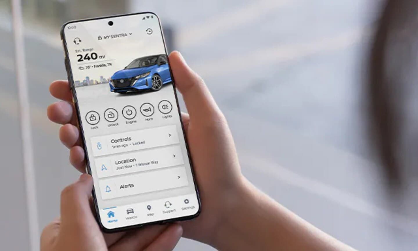 Closeup image of a person holding the MyNissan app looking at their 2025 Nissan Sentra dashboard