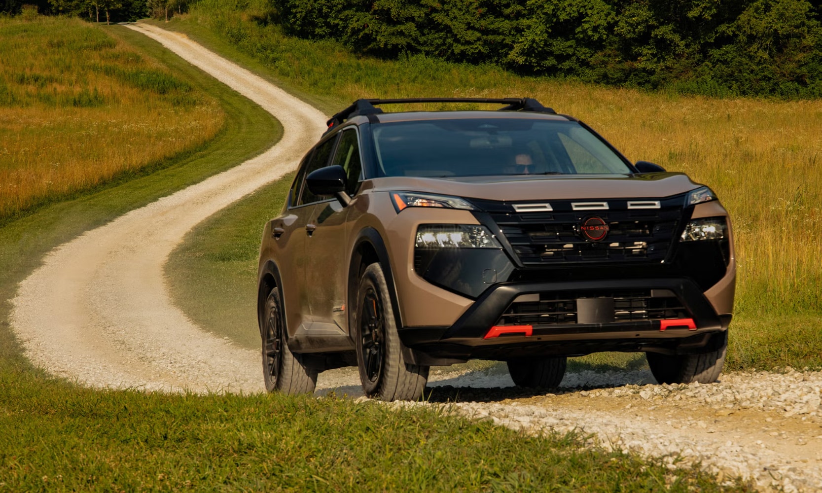 Exterior front image of a 2025 Nissan Rogue Rock Creek Edition driving up a dirt road