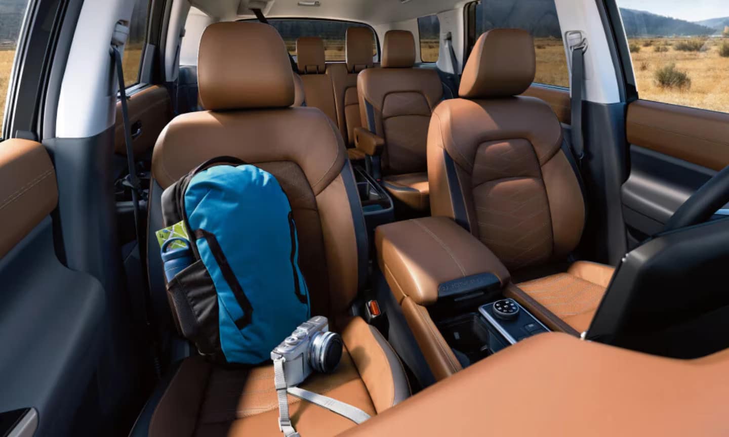 Interior image of 2025 Nissan Pathfinder three-row tan leather seats with school gear on the front seat