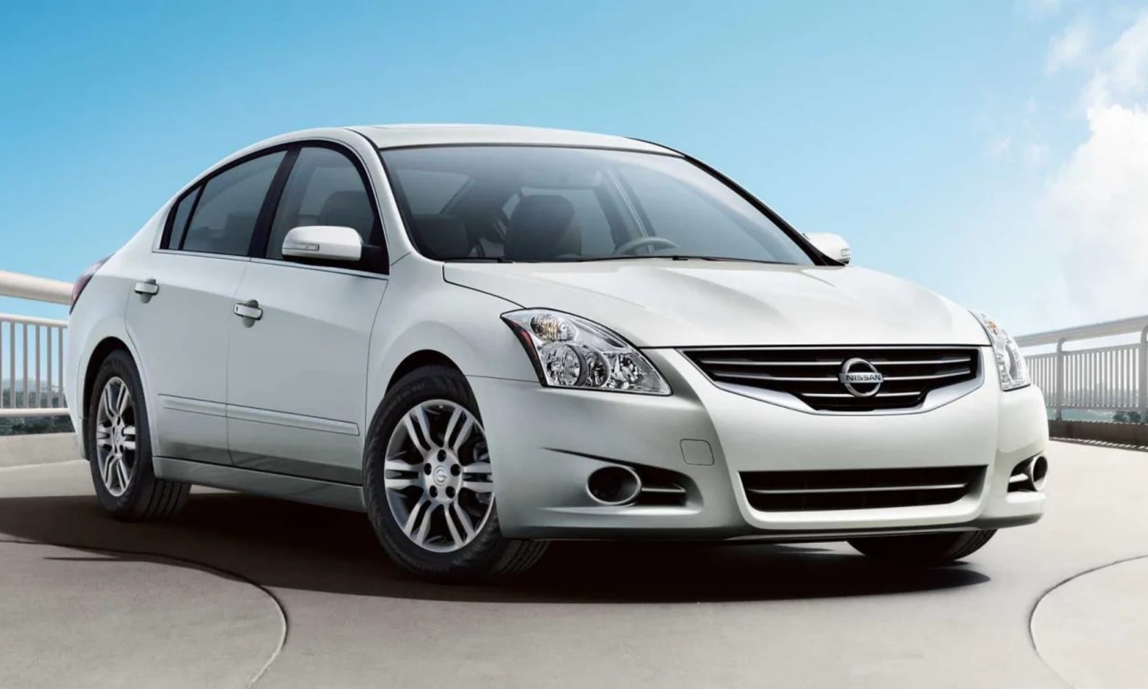 Exterior front side angle image of a white 2011 Nissan Altima parked in a coastal setting