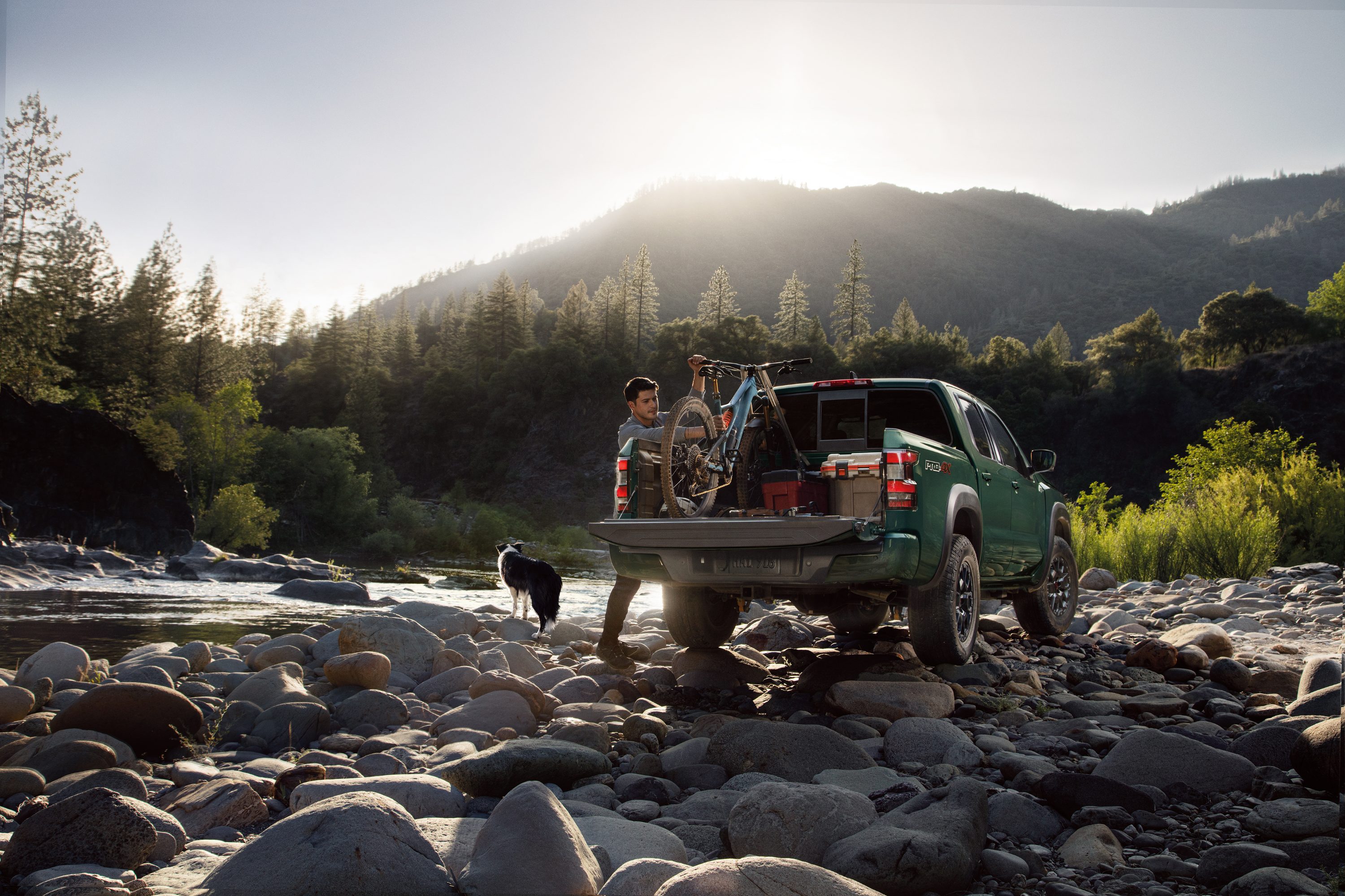 Truck with bike and person with dog parked close to a creek