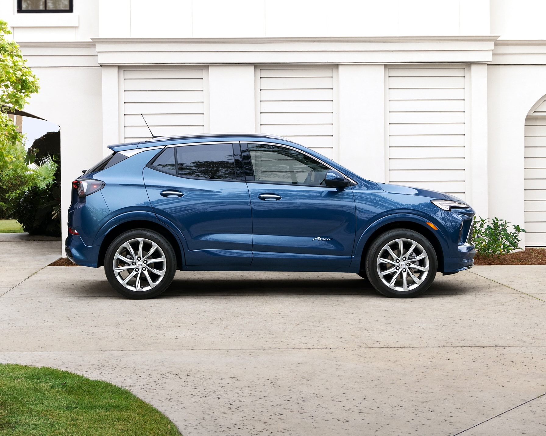 A Side Profile View of a Blue 2025 Buick Encore GX Parked Beside a Home