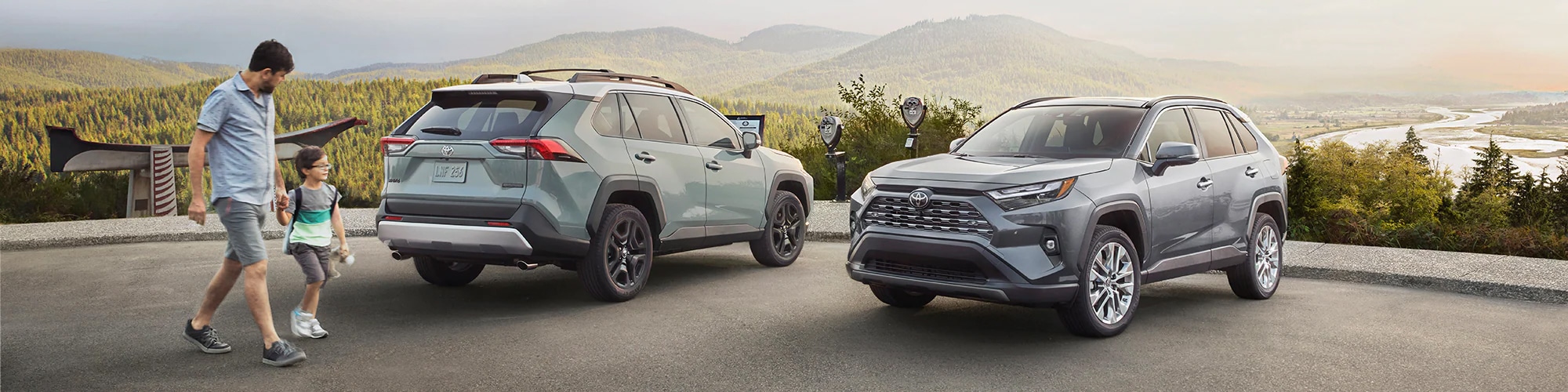 Father and son looking at two New Toyota RAV4 SUVs.